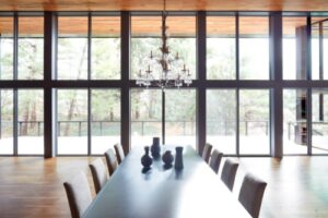 a new dining room with table and expansive windows overlooking a wooded yard